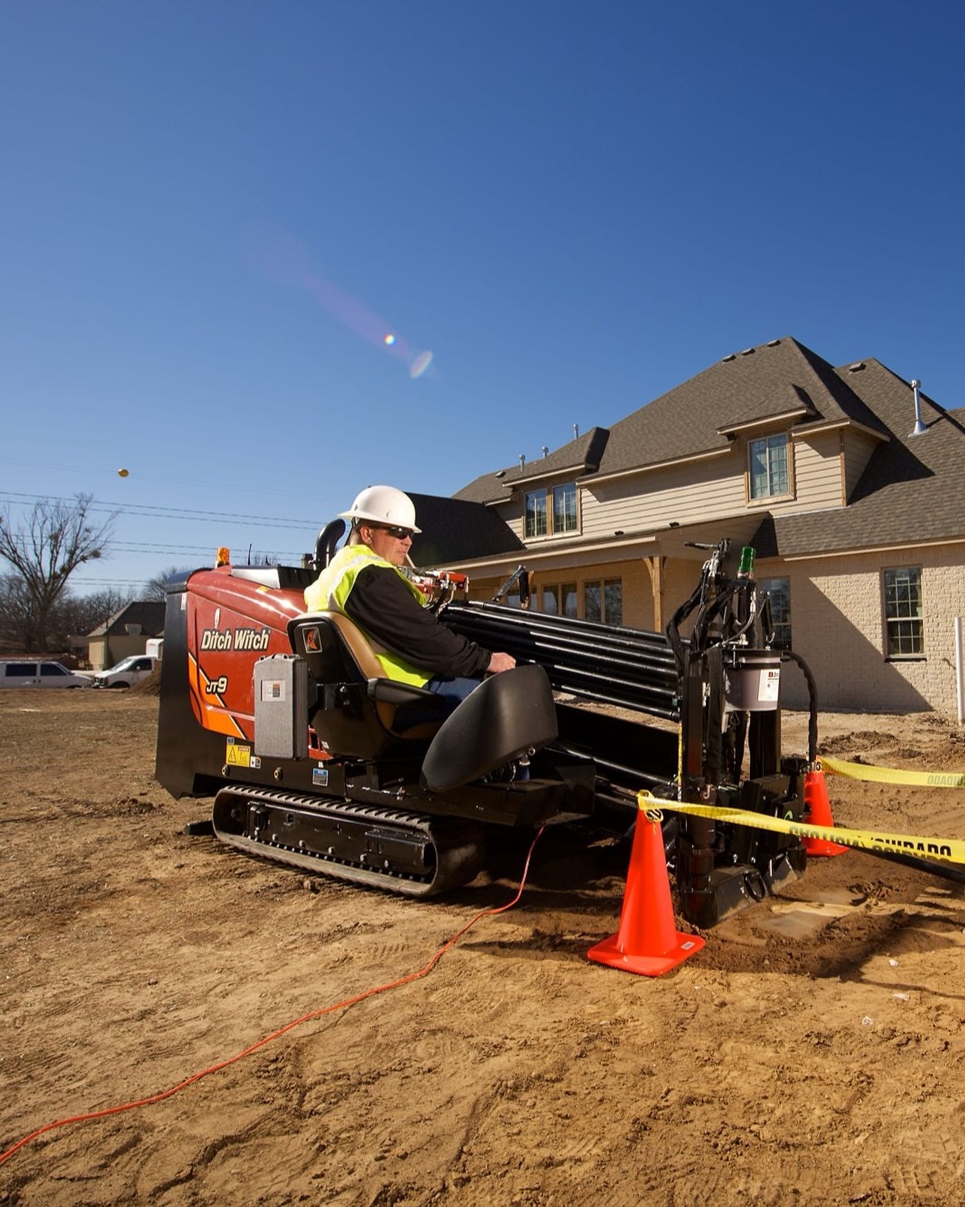 Directional drill operator at work beside a new home